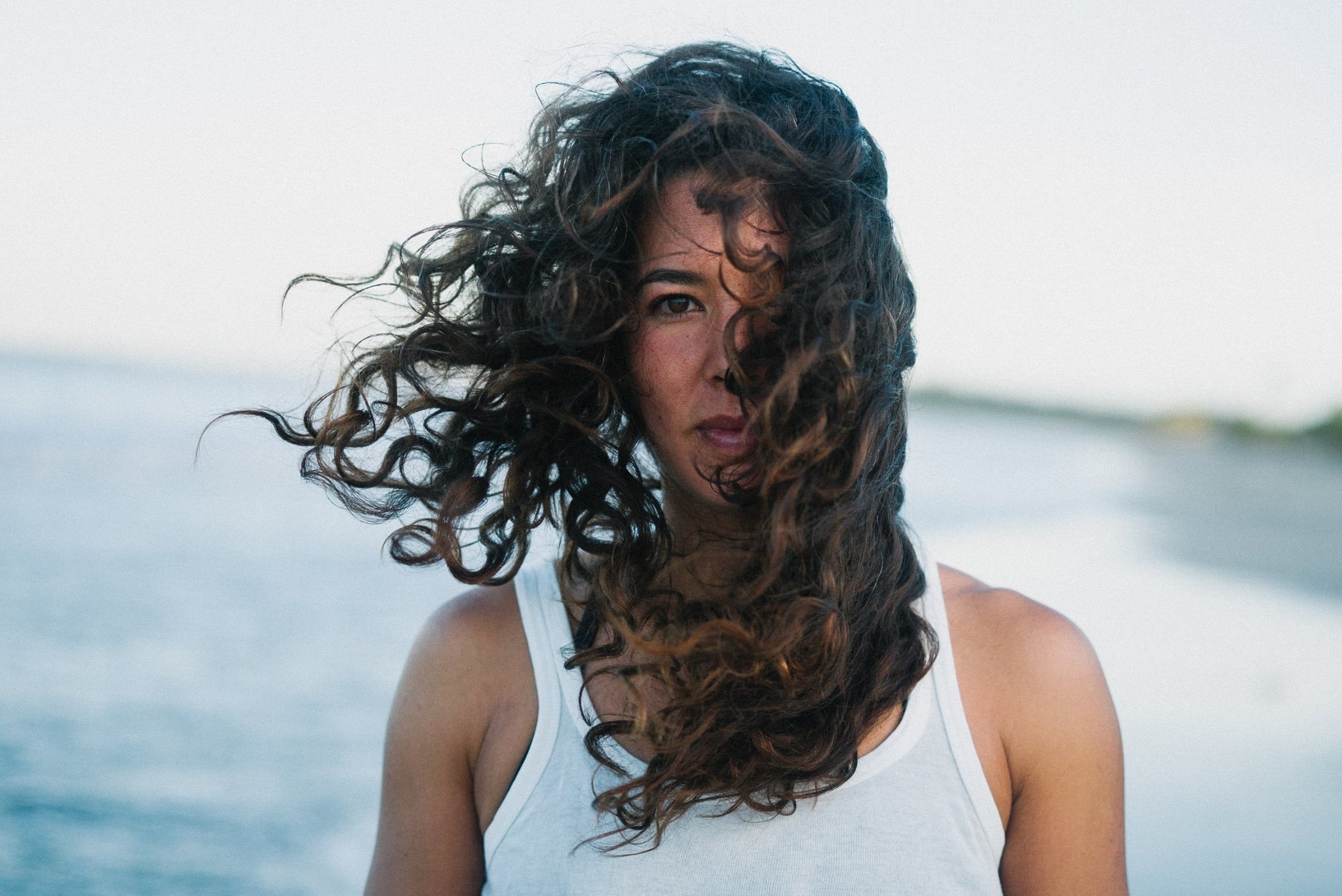 Portrait of Erika Togashi standing on the beach with long hair blowing in her face
