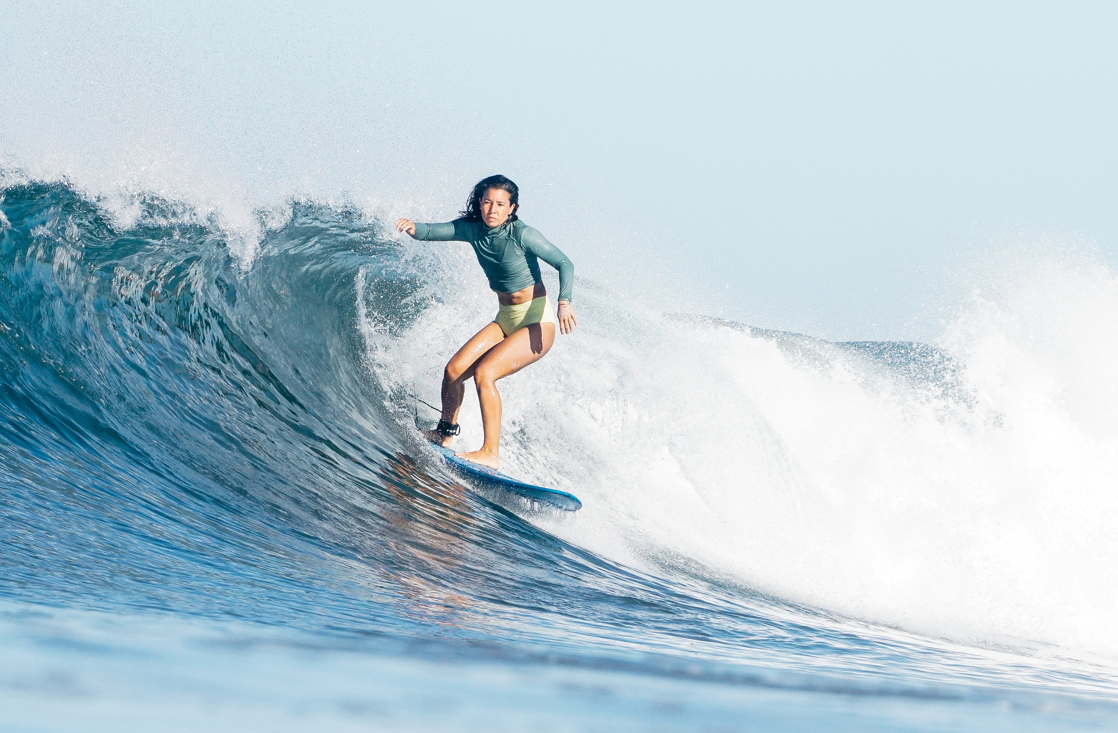 Erika surfing wearing a rash guard and lucky high waisted surf bikini bottoms 