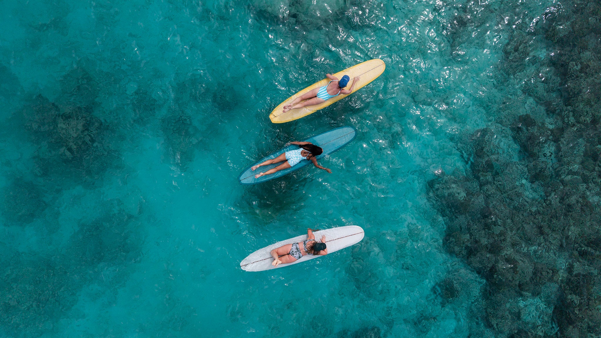Three people on surfboards in clear blue water