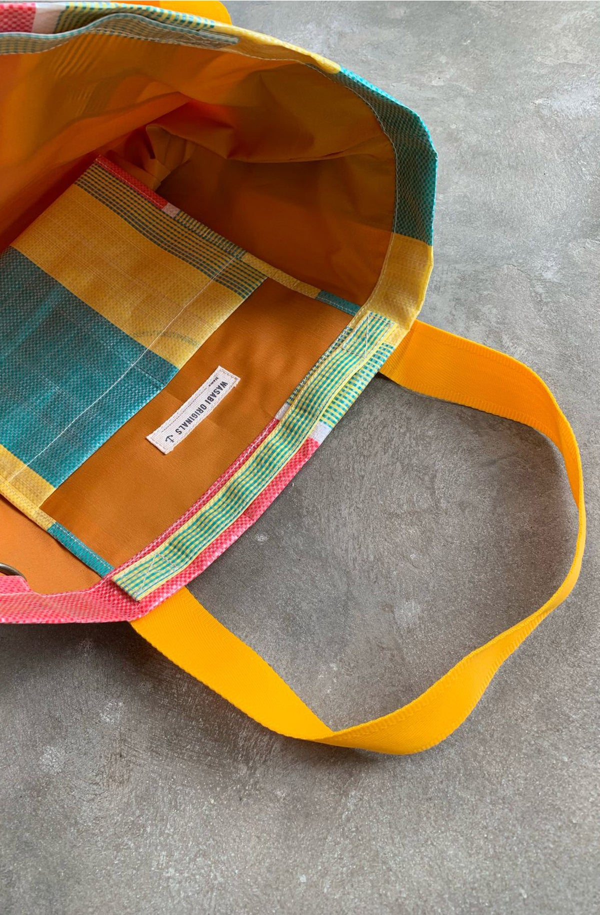 Colorful tote bag with a visible brand label on a gray surface. Bingin tote bags