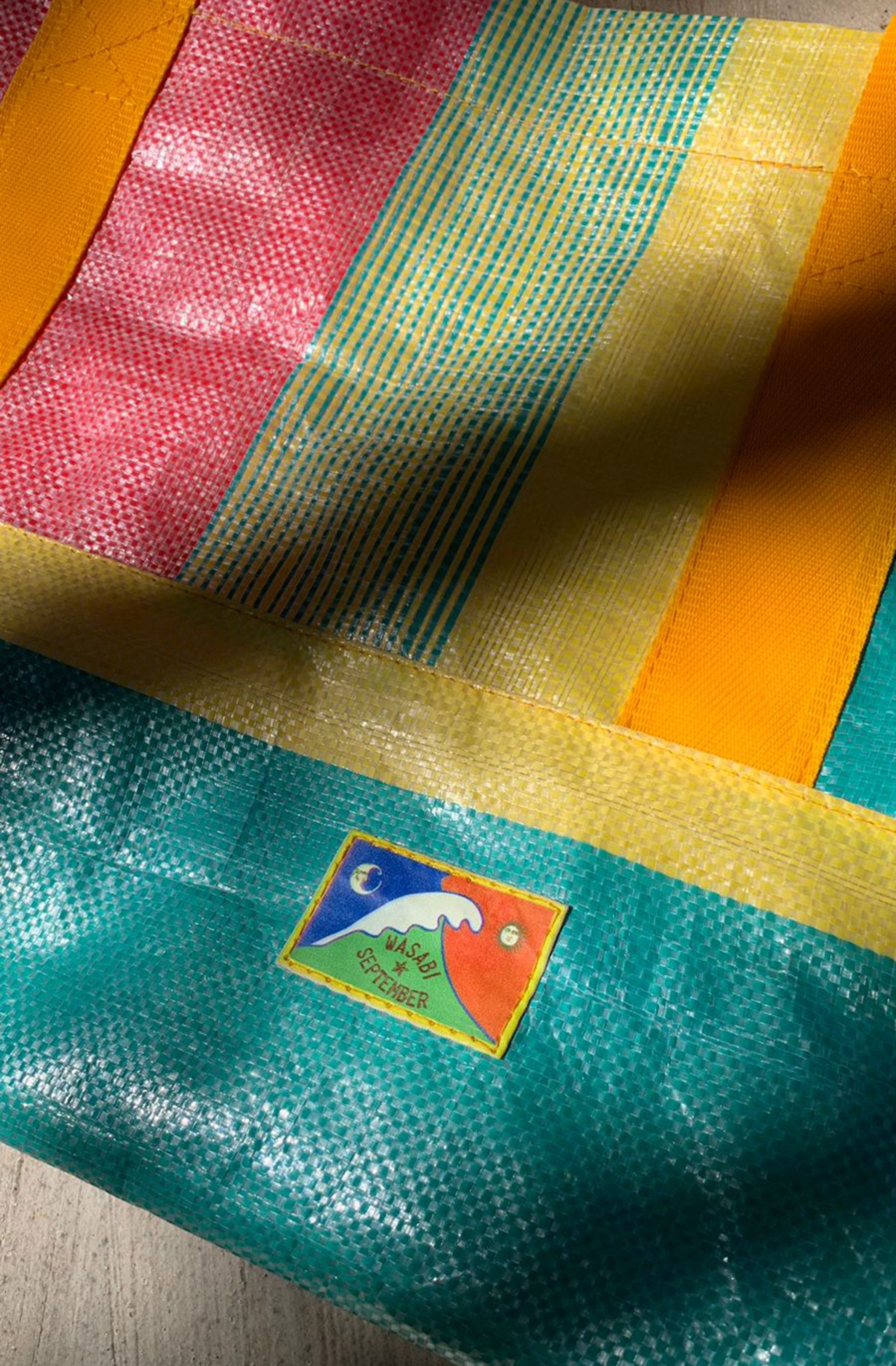Colorful fabric with a logo on a wooden surface  Bingin tote bags
