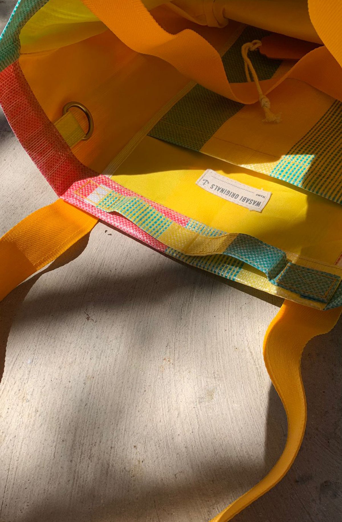 Close-up of a colorful bag with a visible brand label on a wooden surface Bingin tote bags