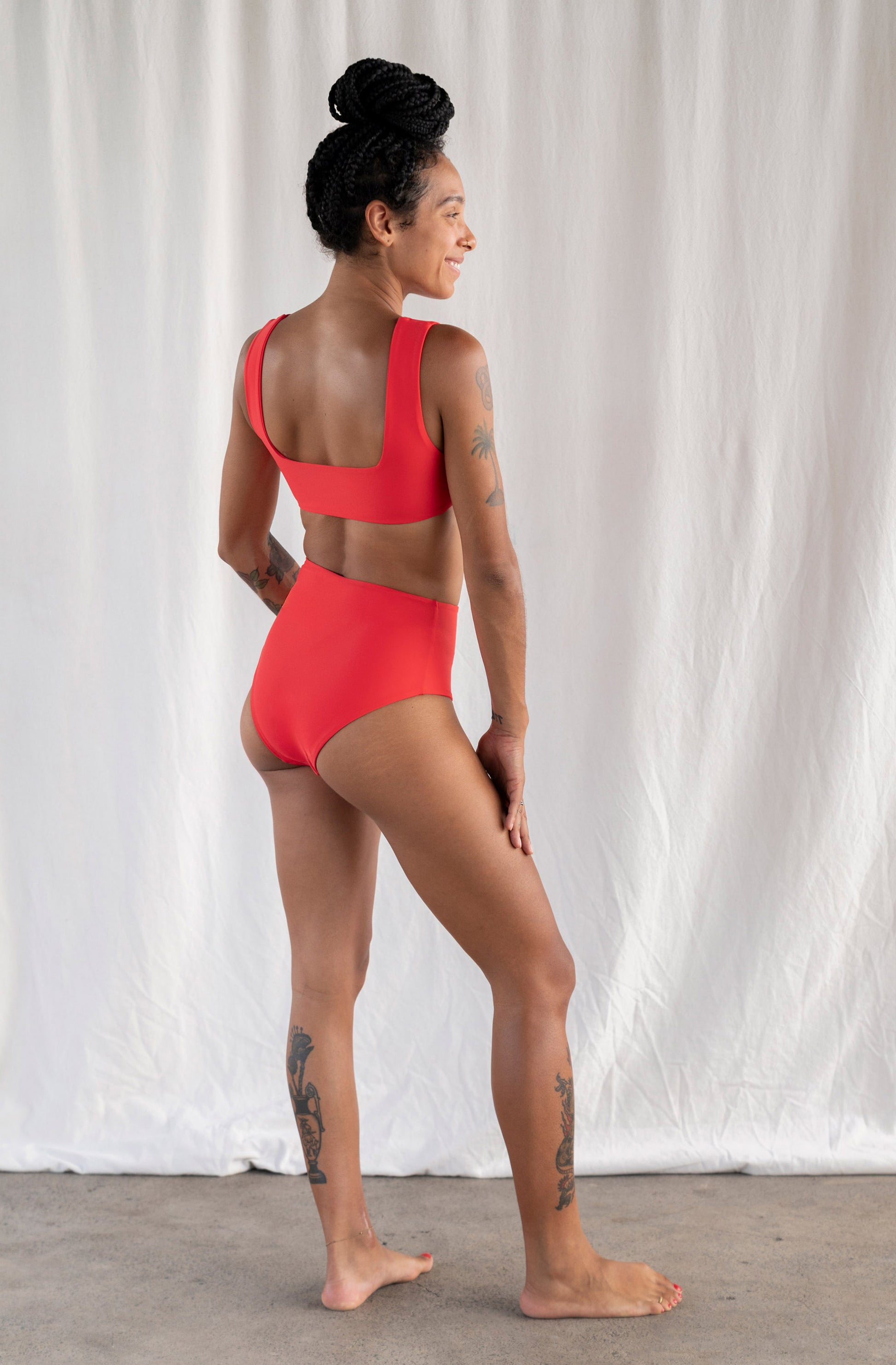 Person wearing a red swimsuit against a white curtain background