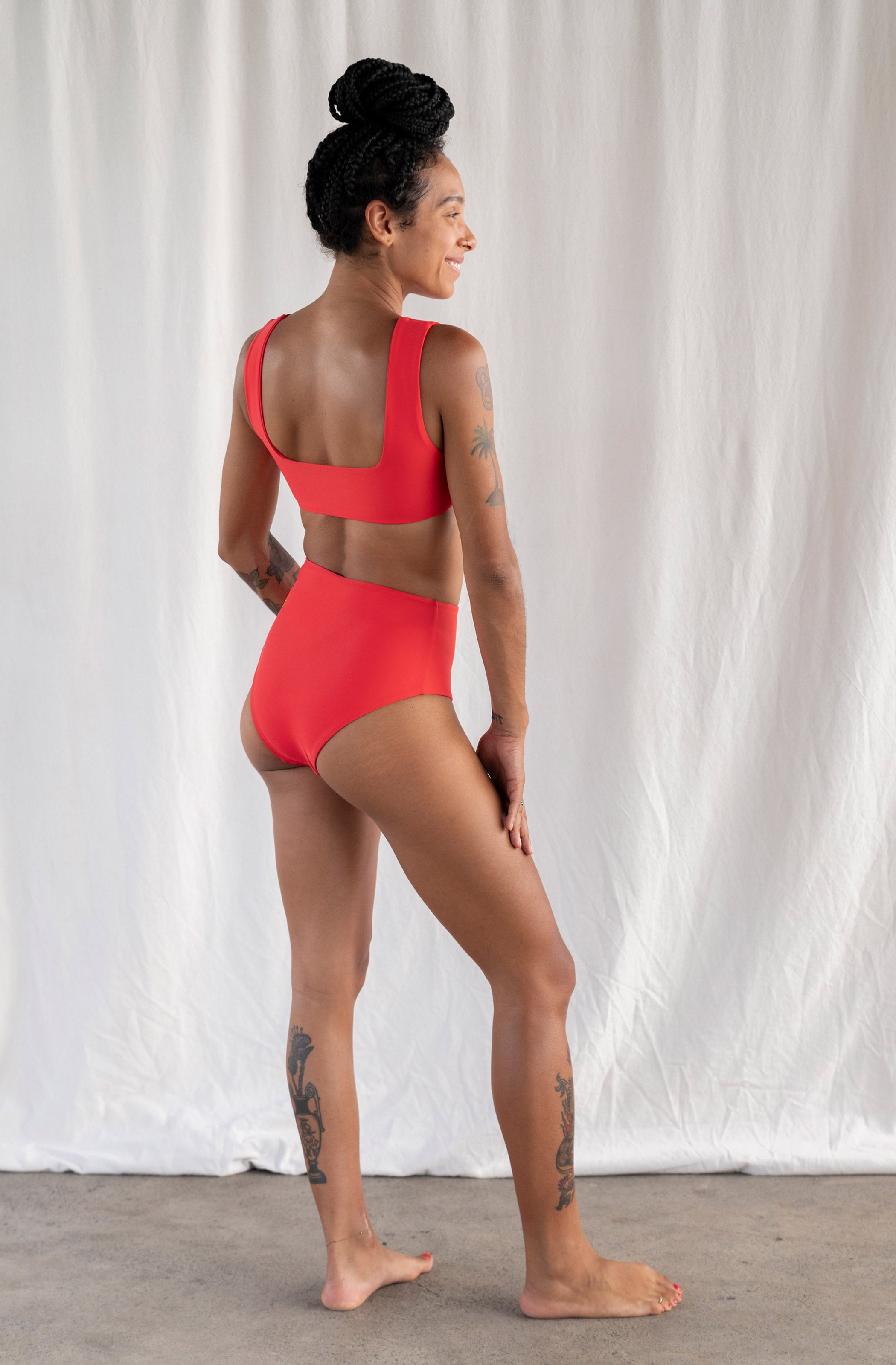 Person wearing a red swimsuit against a white curtain background