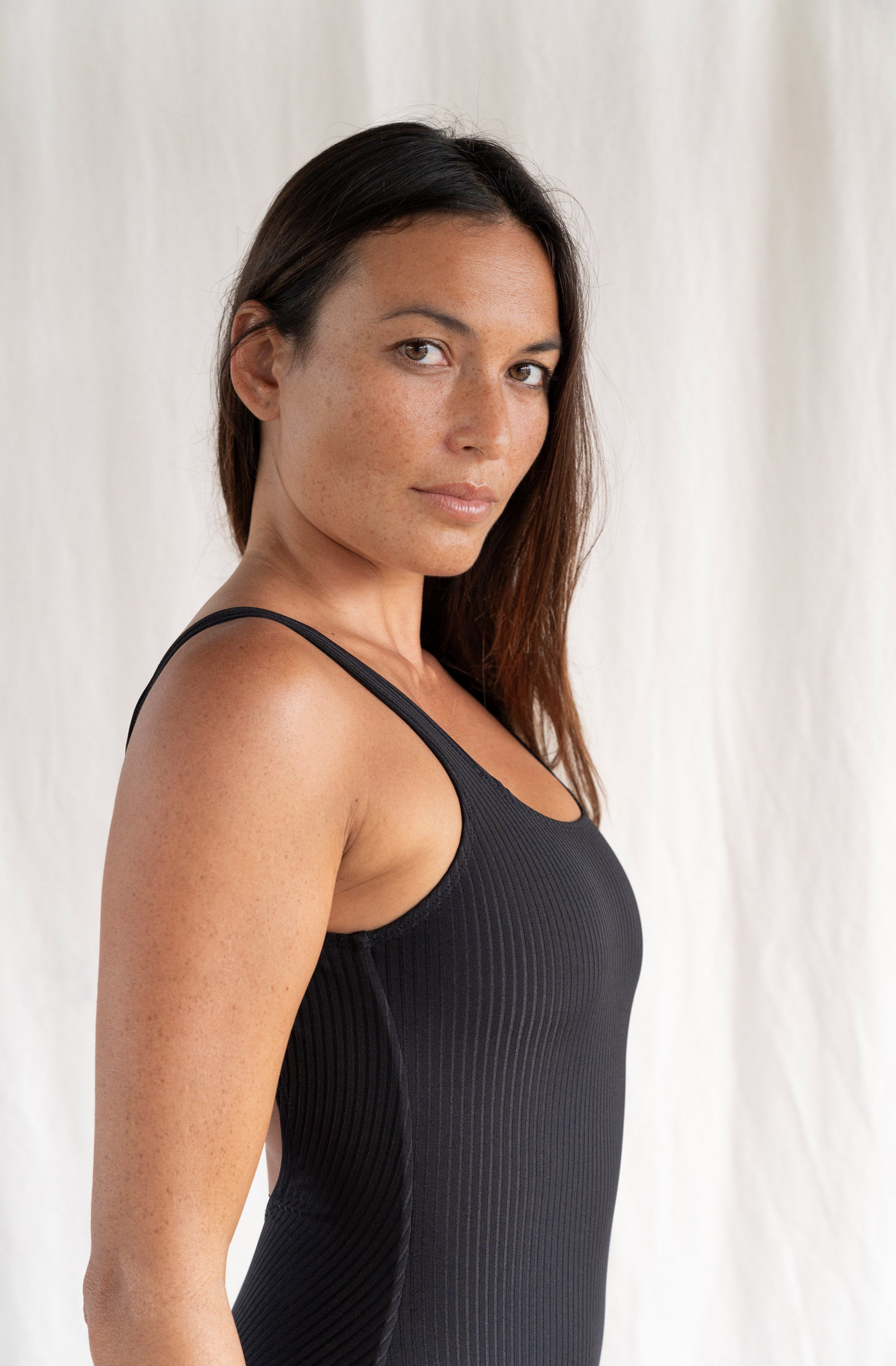 Woman wearing a black sleeveless top against a white background