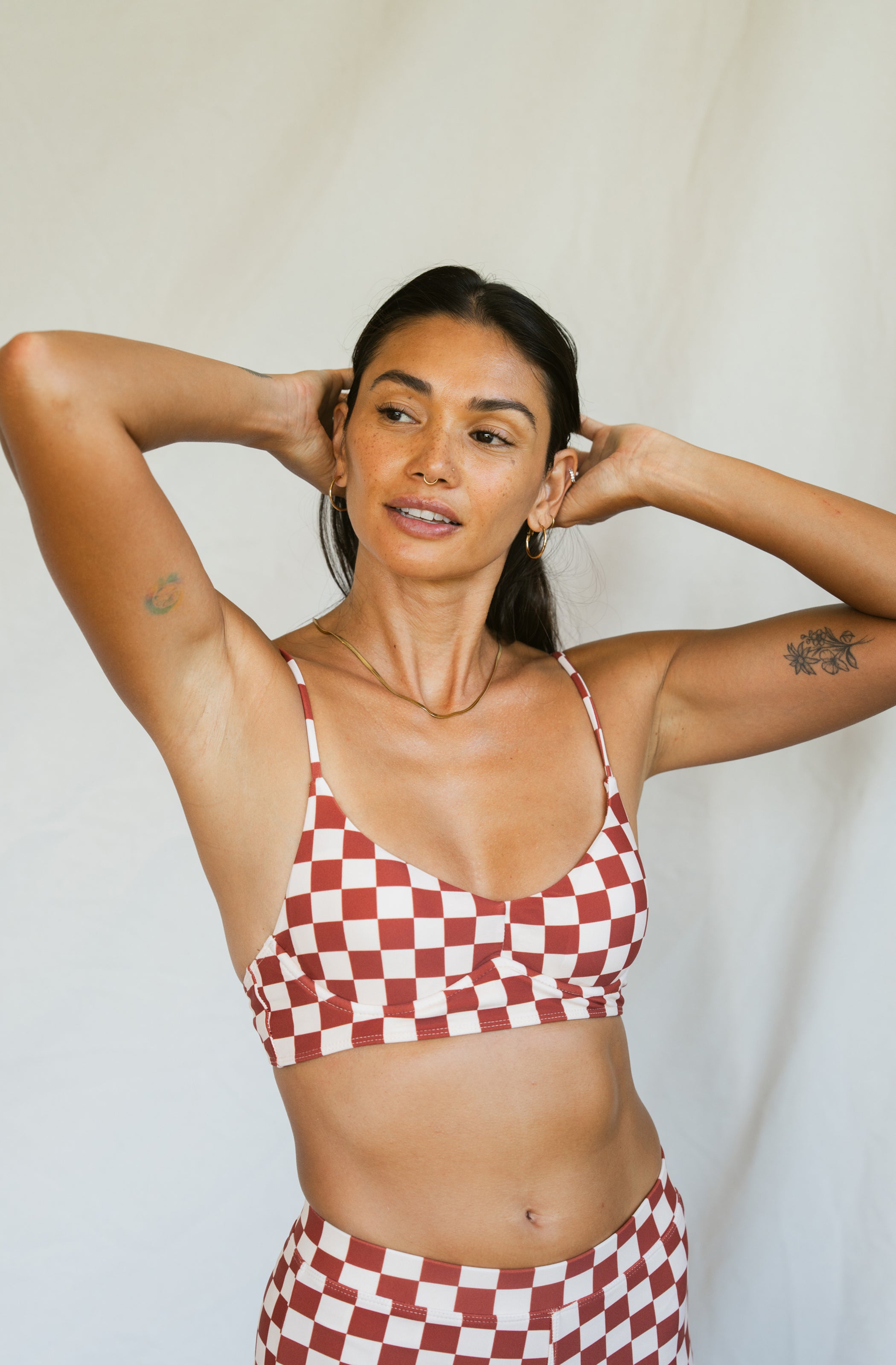 Woman wearing a red and white checkered bikini against a plain background