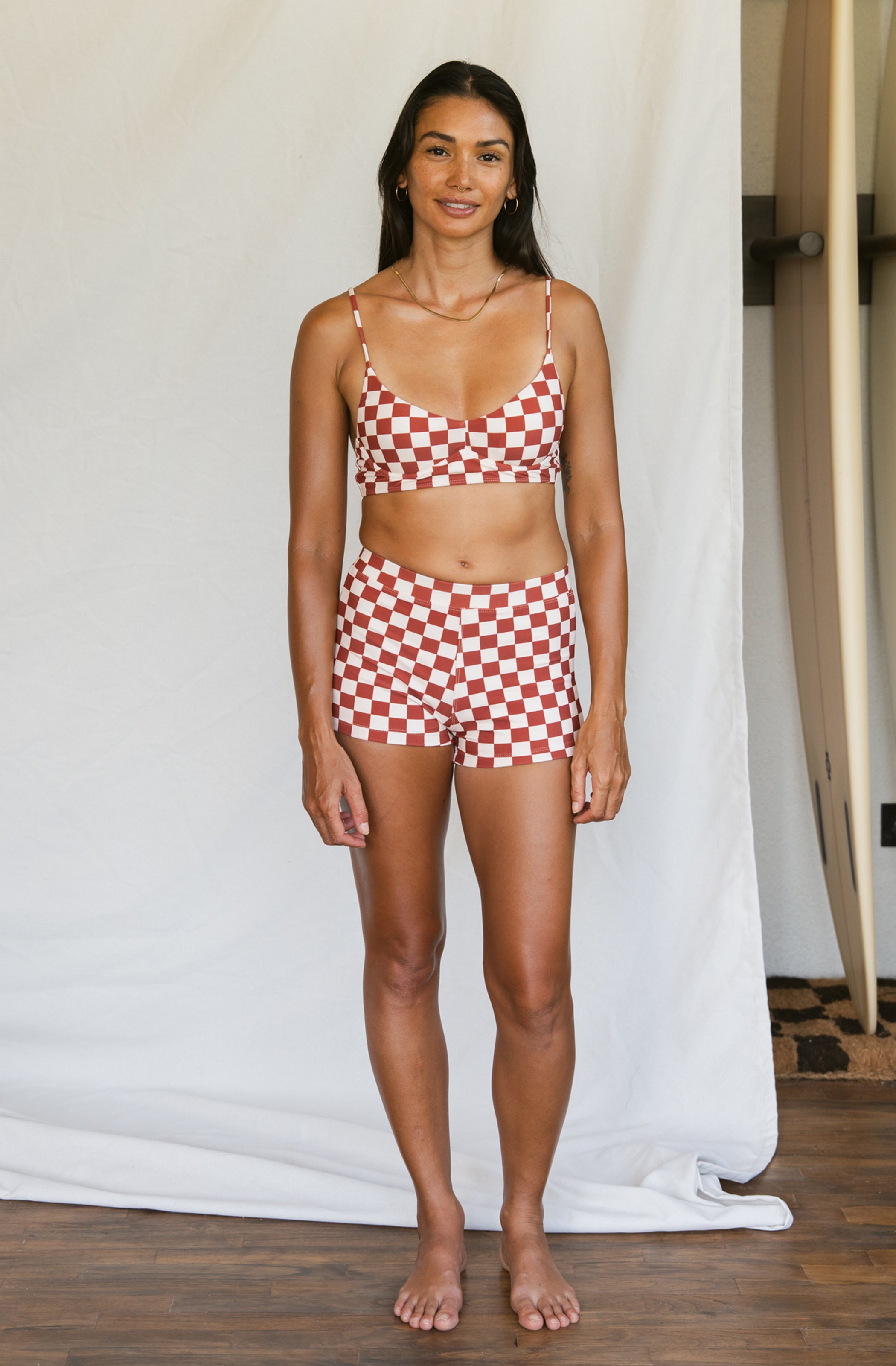 Woman wearing a red and white checkered bikini set against a neutral background