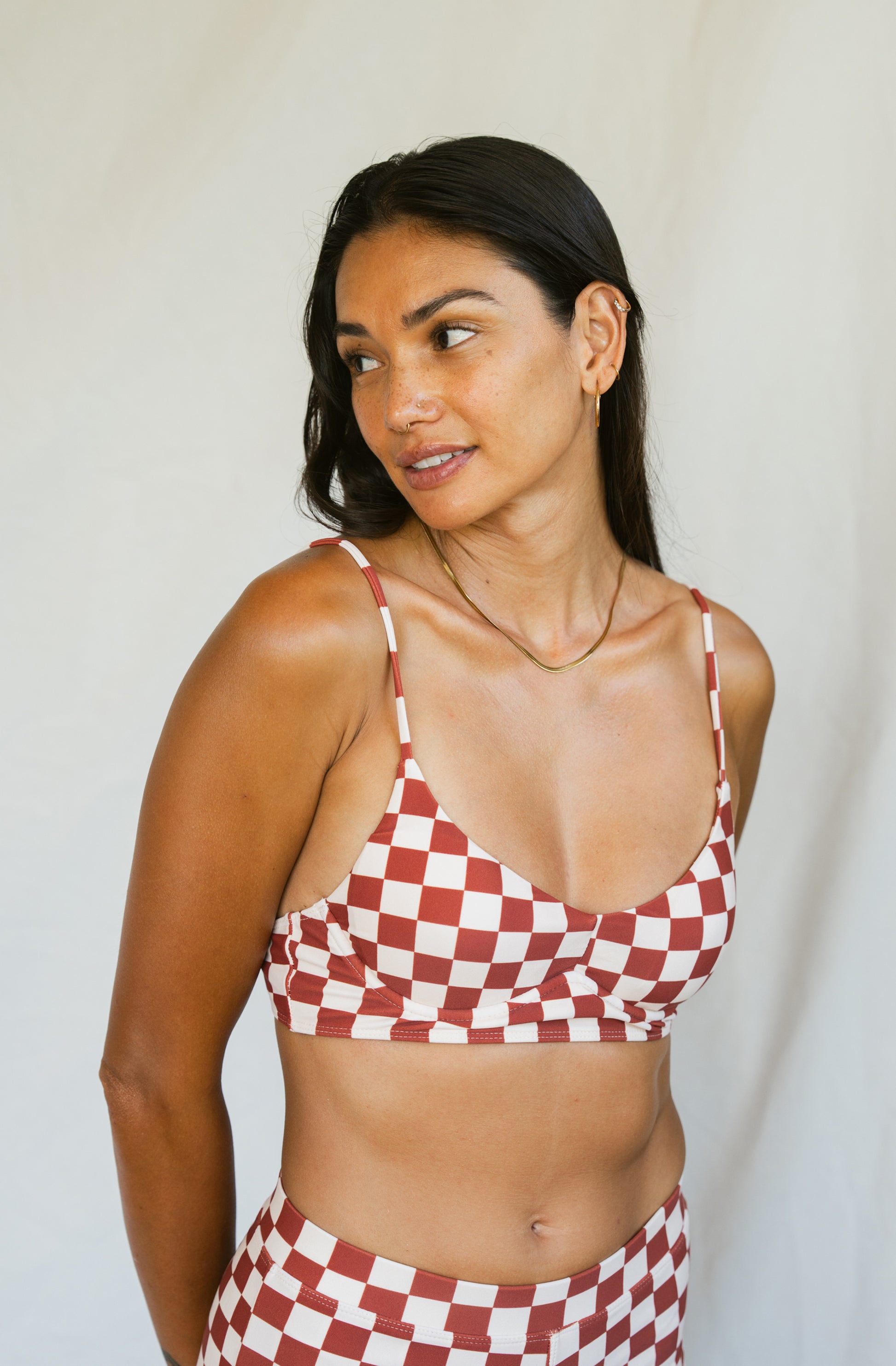 Woman wearing a red and white checkered bikini against a plain background