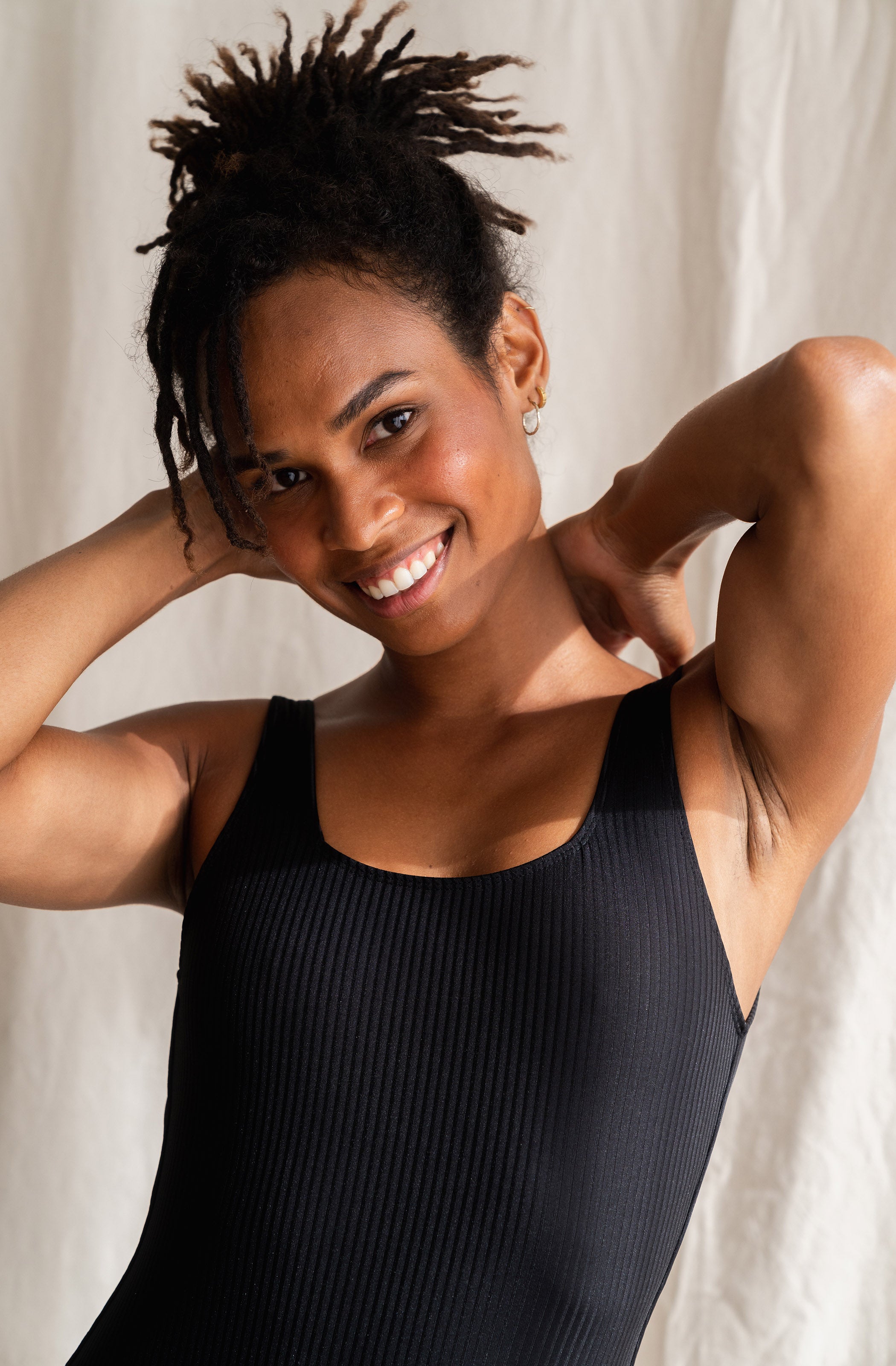 Woman wearing a black sleeveless top against a neutral background