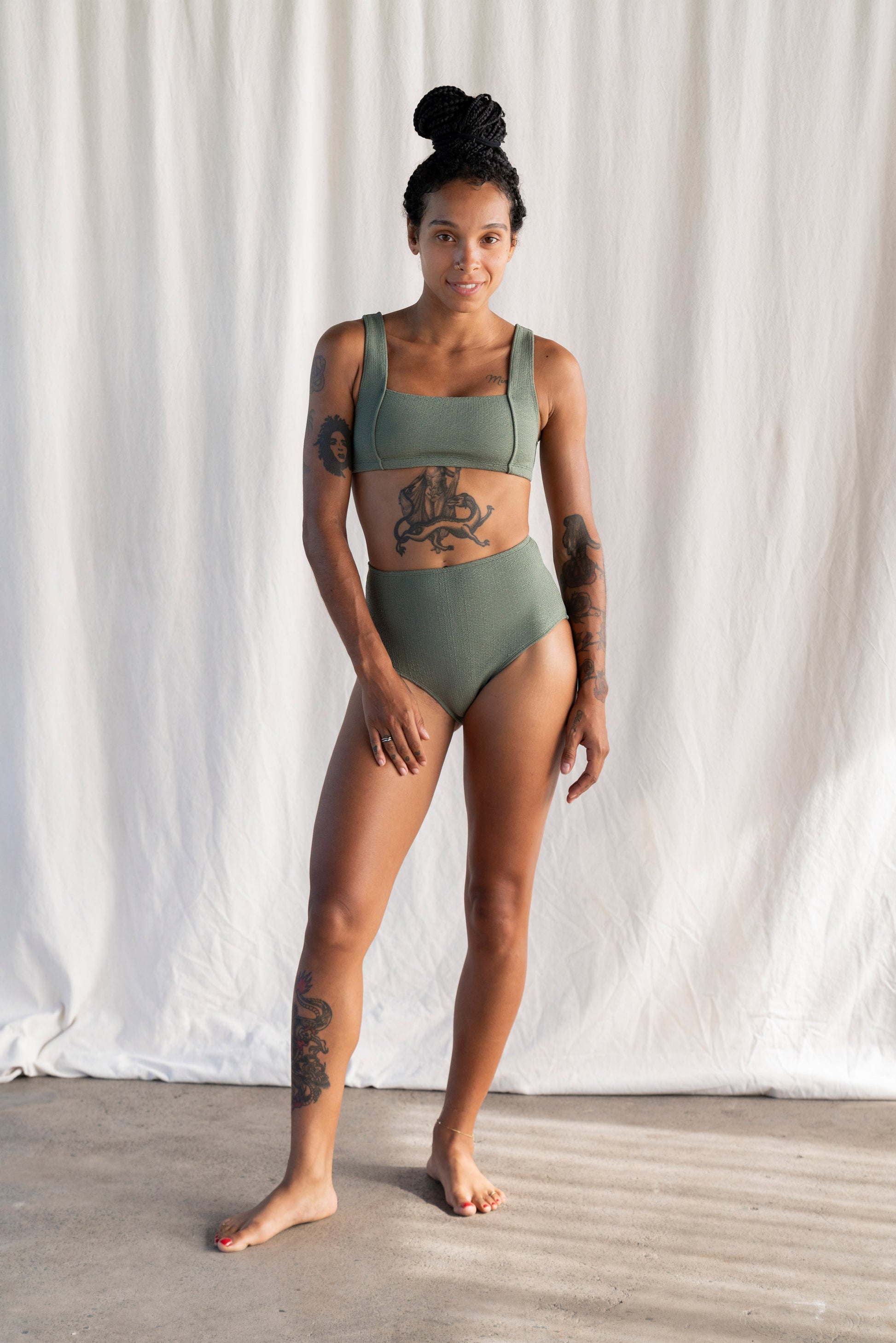 Person wearing a green bikini set against a white curtain background