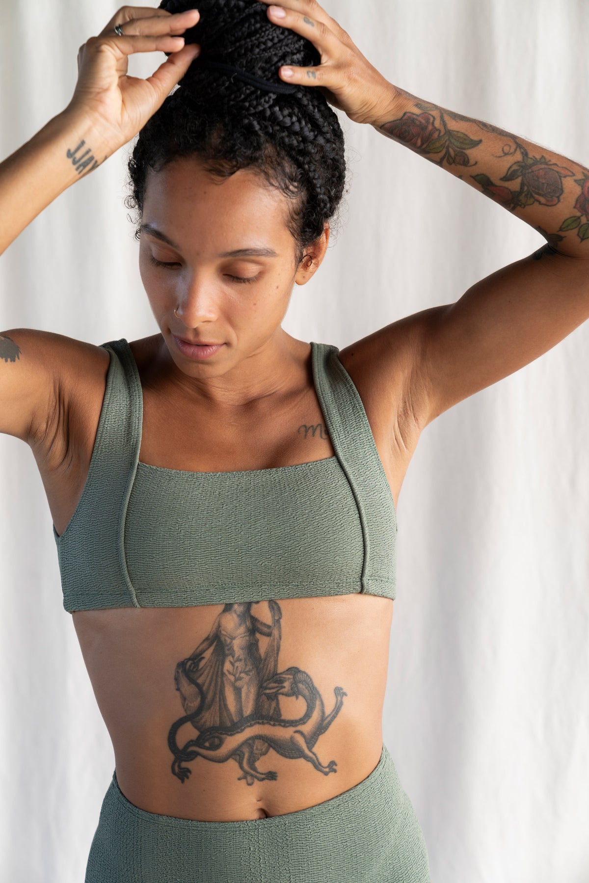 Woman wearing a green sports bra and leggings against a white background