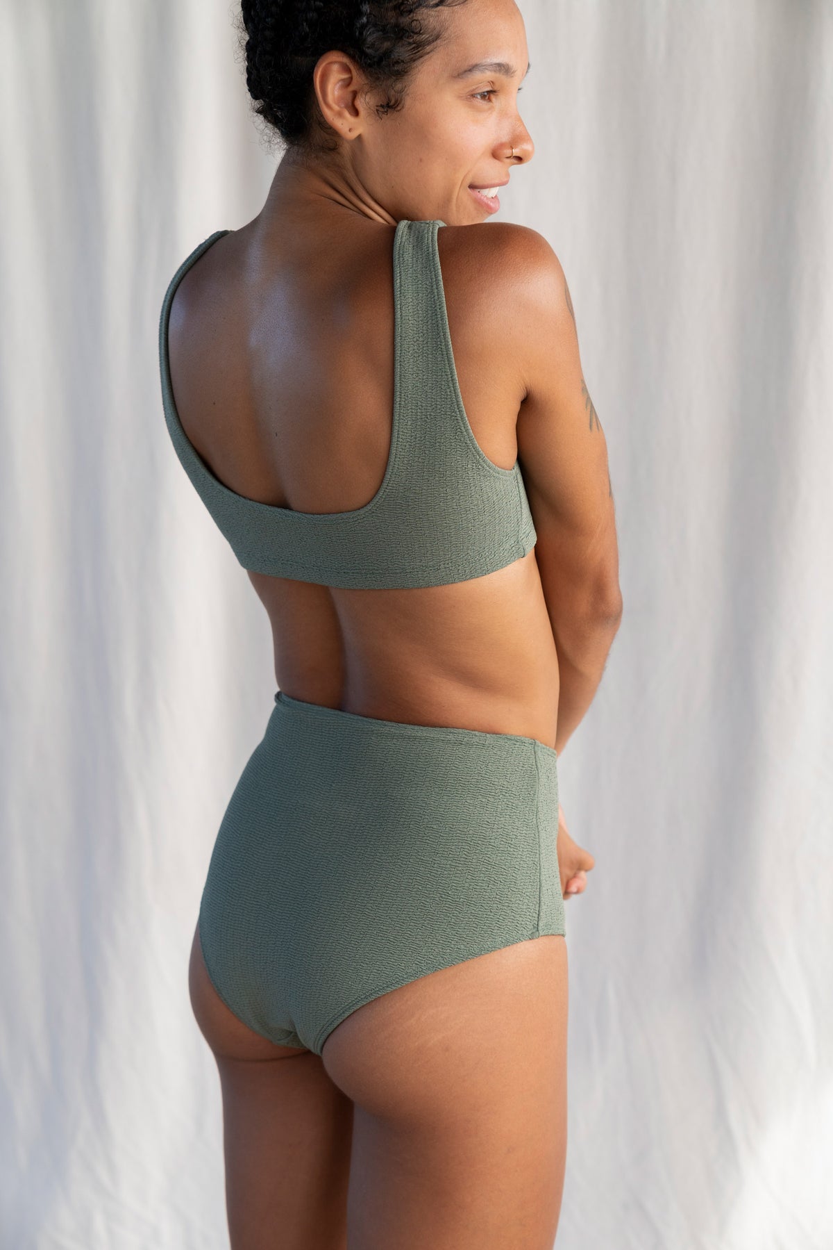 Woman wearing a green bikini set against a neutral background