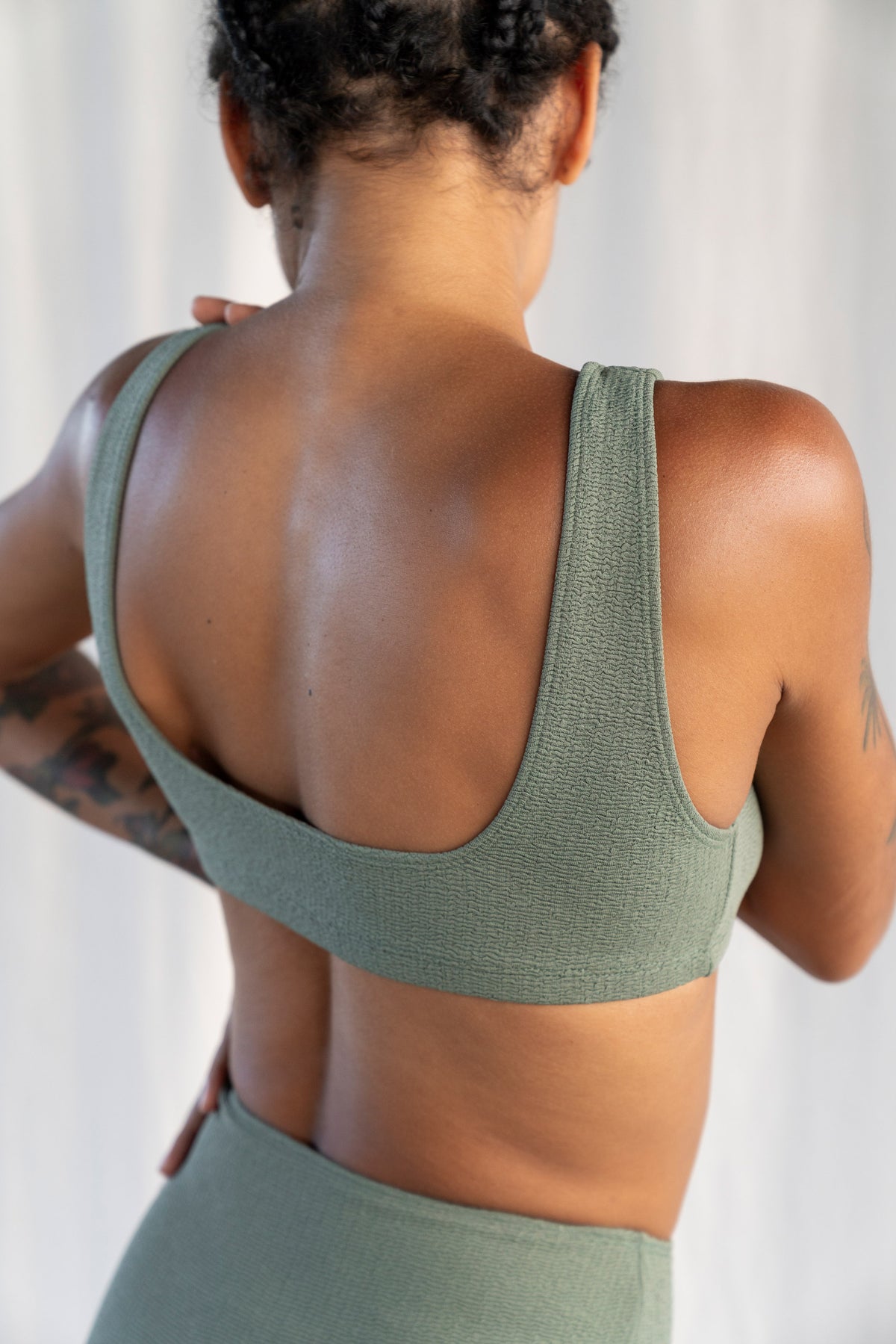 Person wearing a green sports bra and leggings against a white background