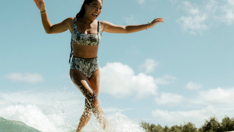 Woman surfing on a wave with a clear blue sky in the background