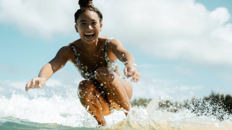 Woman surfing on a wave with a clear sky in the background