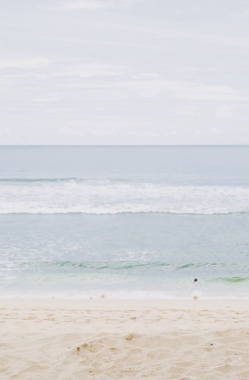 Woman standing in front of ocean wearing    Surf_One_Piece_Marigold_Sangria_Red