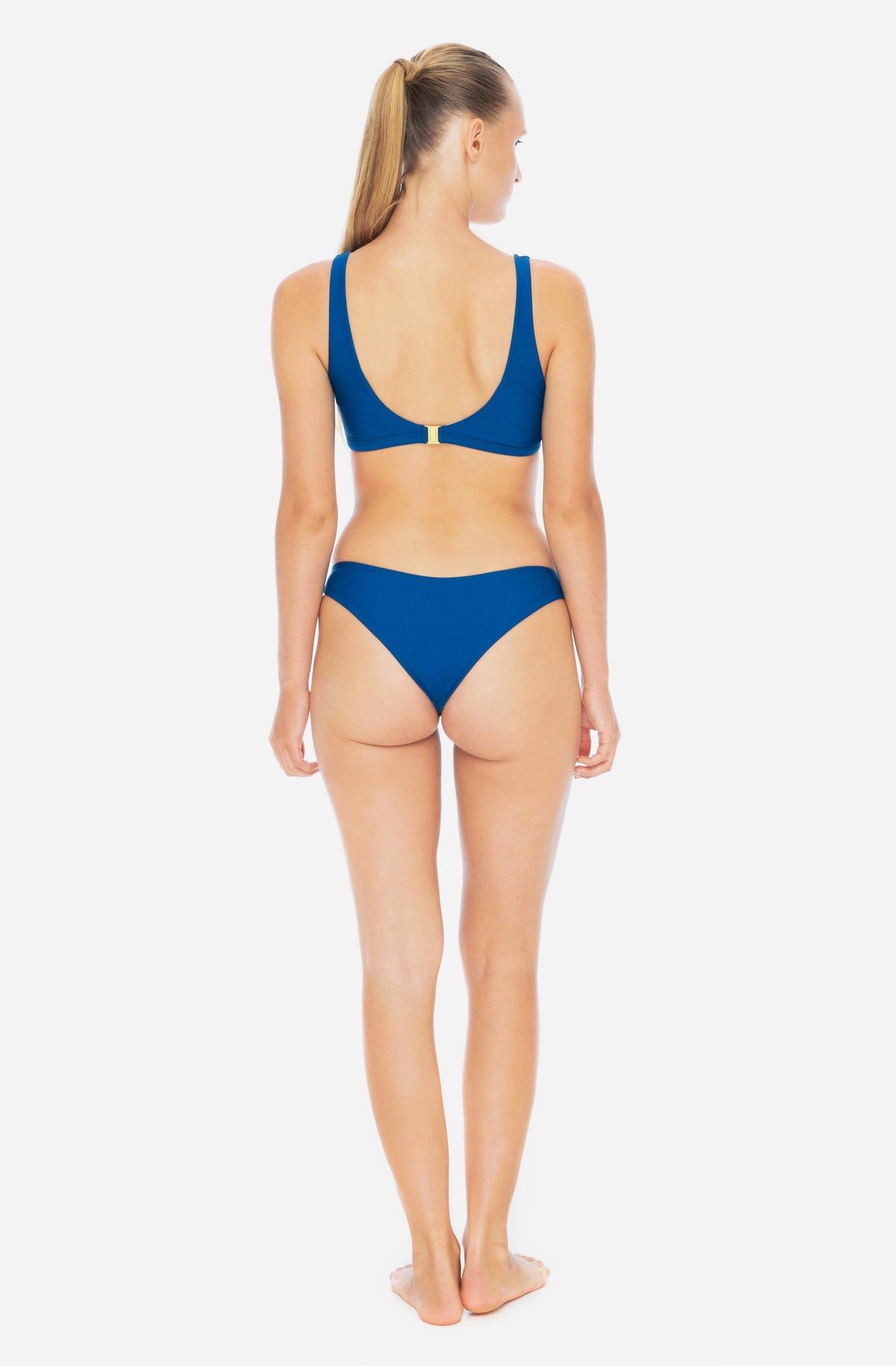 Back view of  woman wearing triangle top surf bikini top and bottom in lake blue