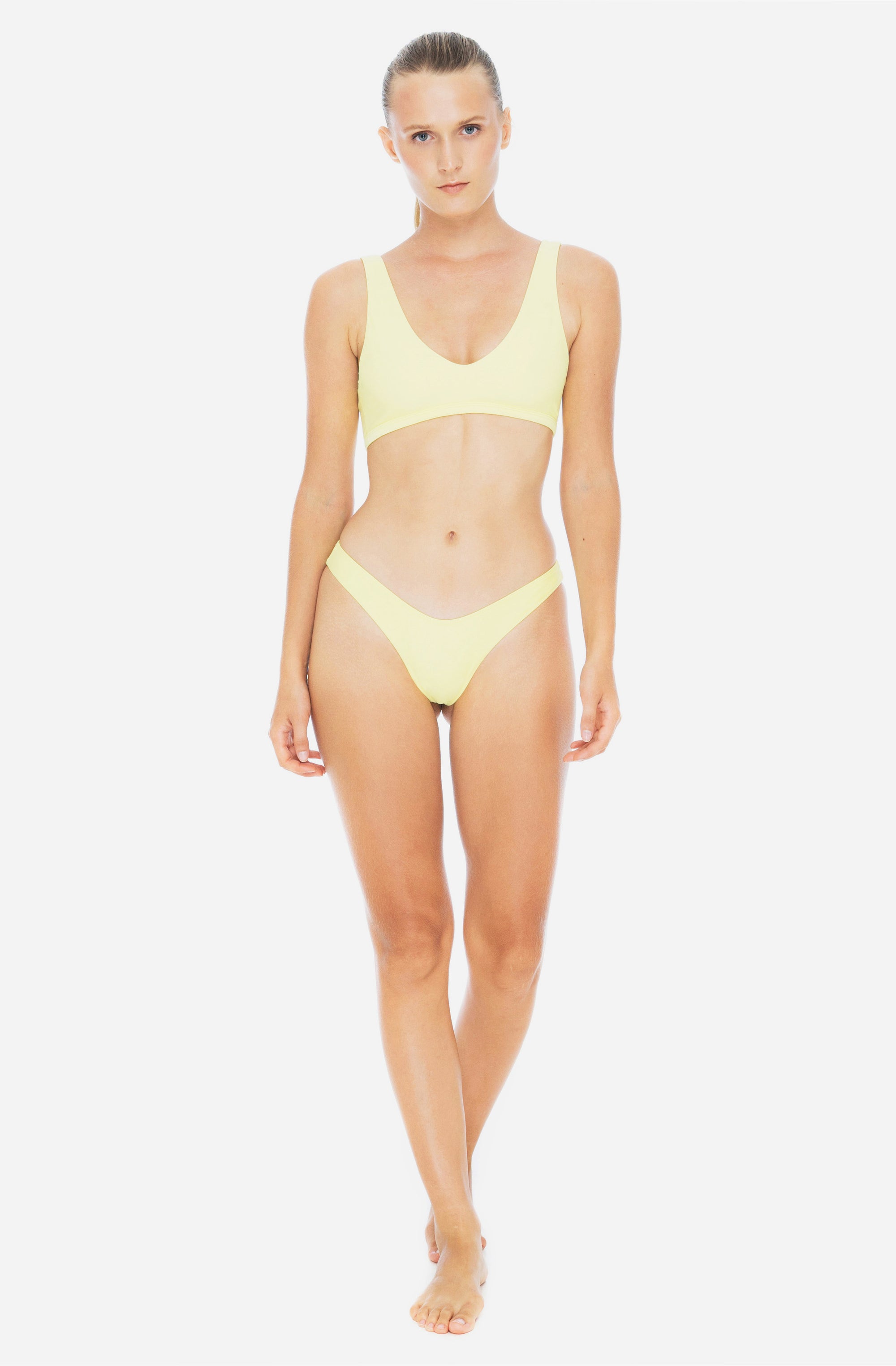 Woman modeling a triangle top surf bikini top and bottom in sunflower yellow