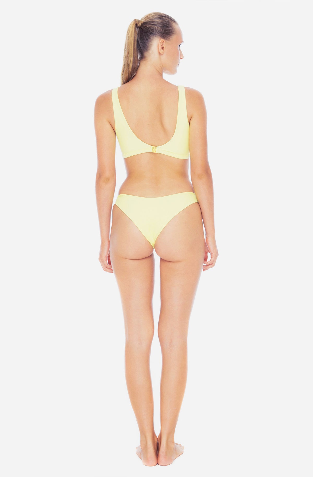 Back view of a woman modelling a surf bikini top and a surf bikini bottom in sunflower yellow.