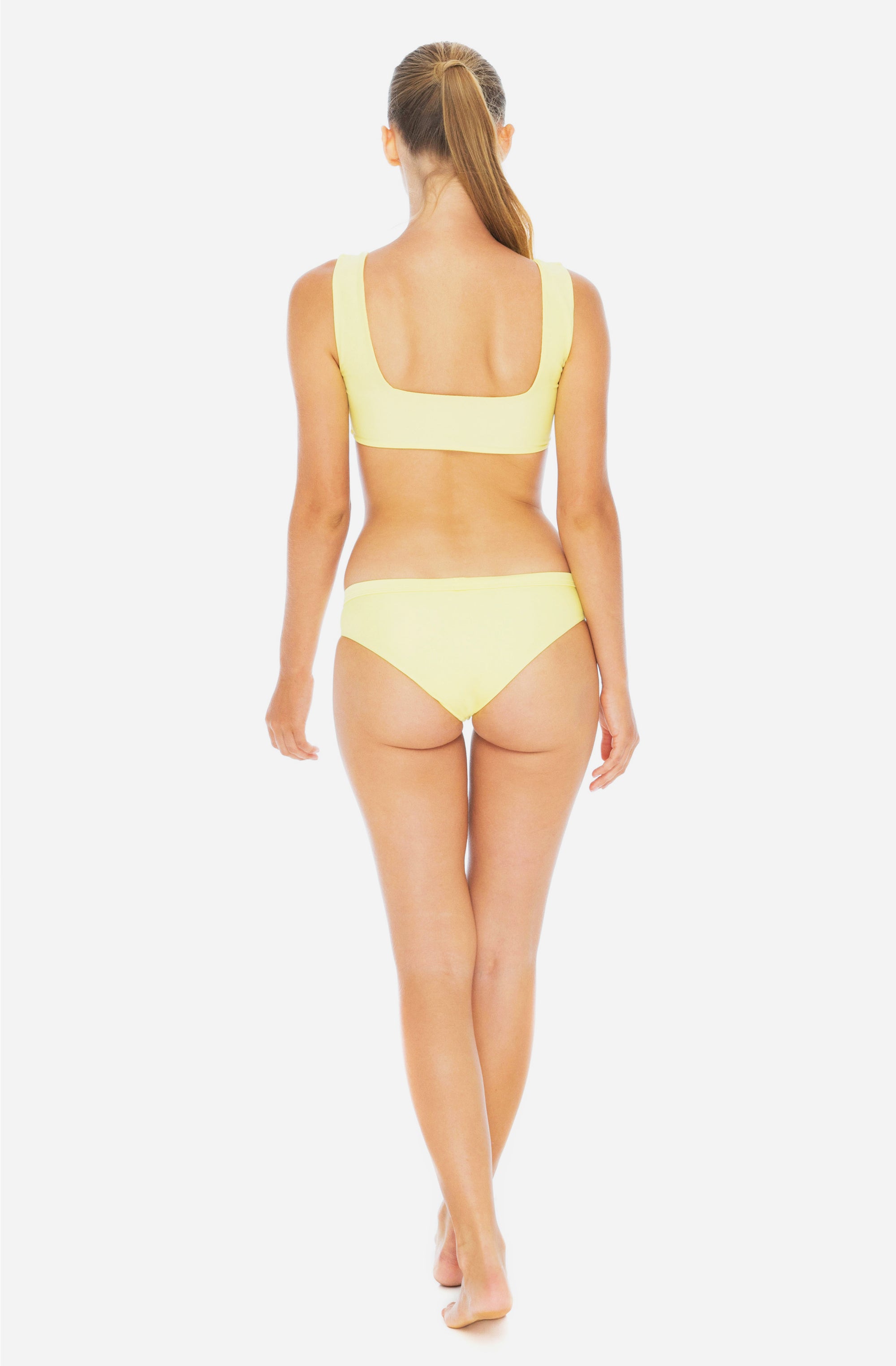 Front view of a woman modelling a surf bikini top and a surf bikini bottom in sunflower yellow.
