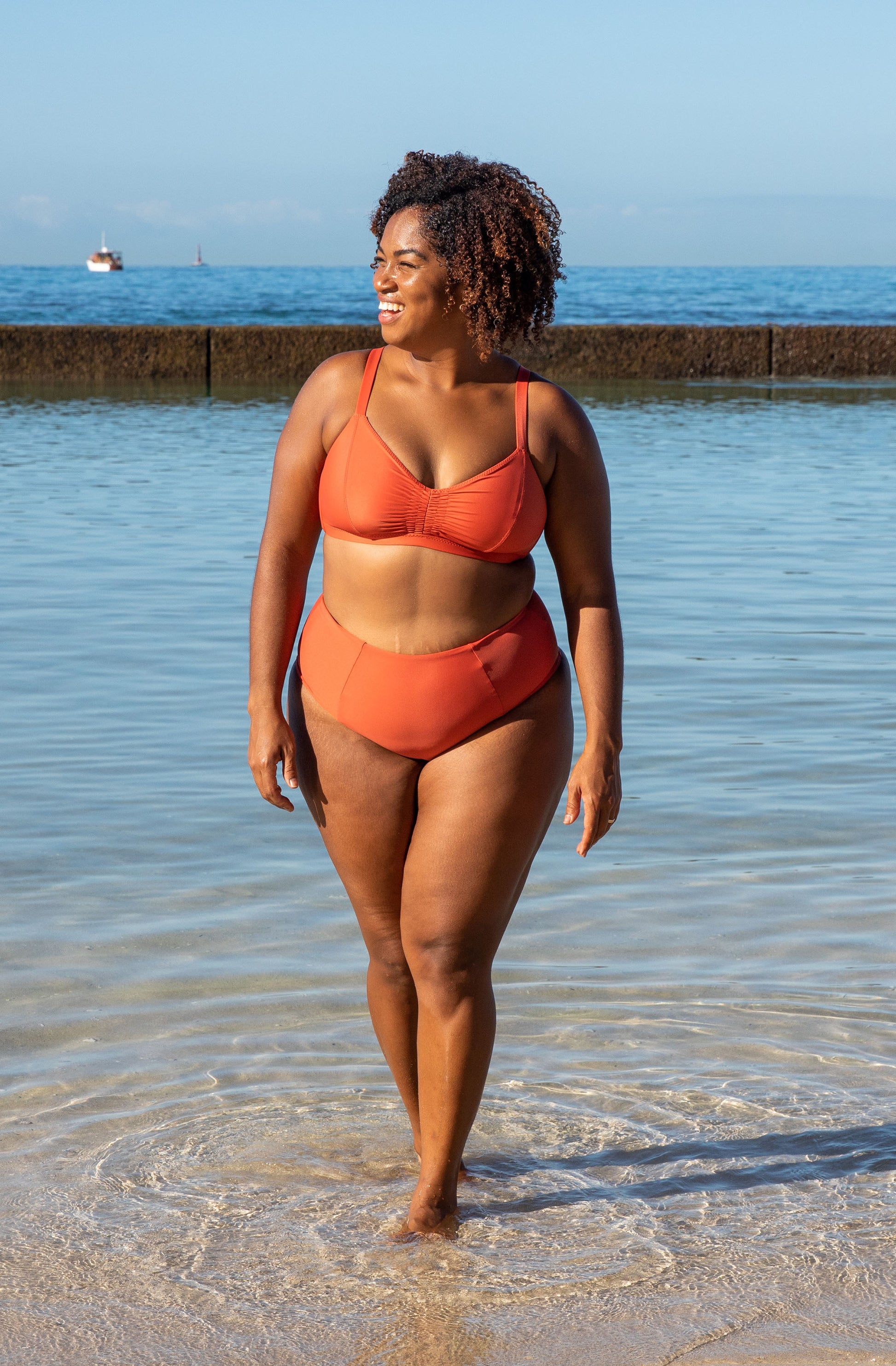 woman smiling in the beach wearing the lori bikini and alice bottoms in burnt sienna