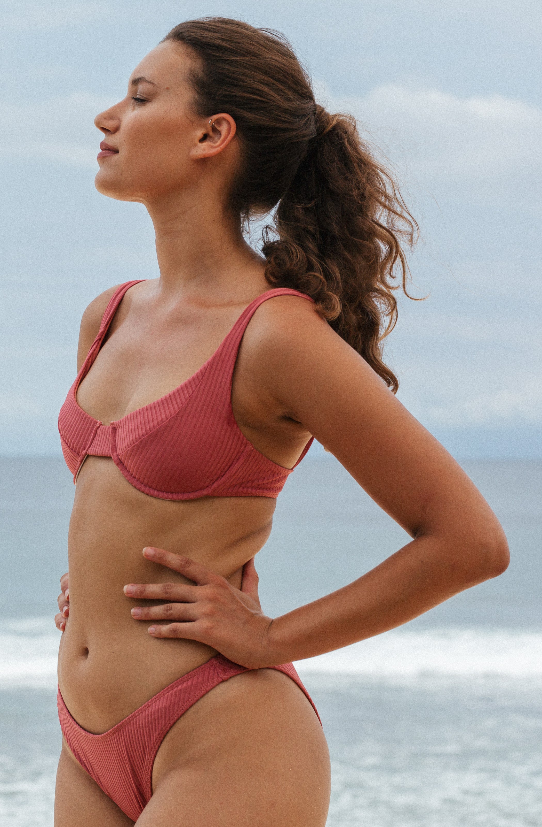 Woman standing in front of ocean wearing Surf_Bikini_Top_Rita_Guava_Eco_Rib
