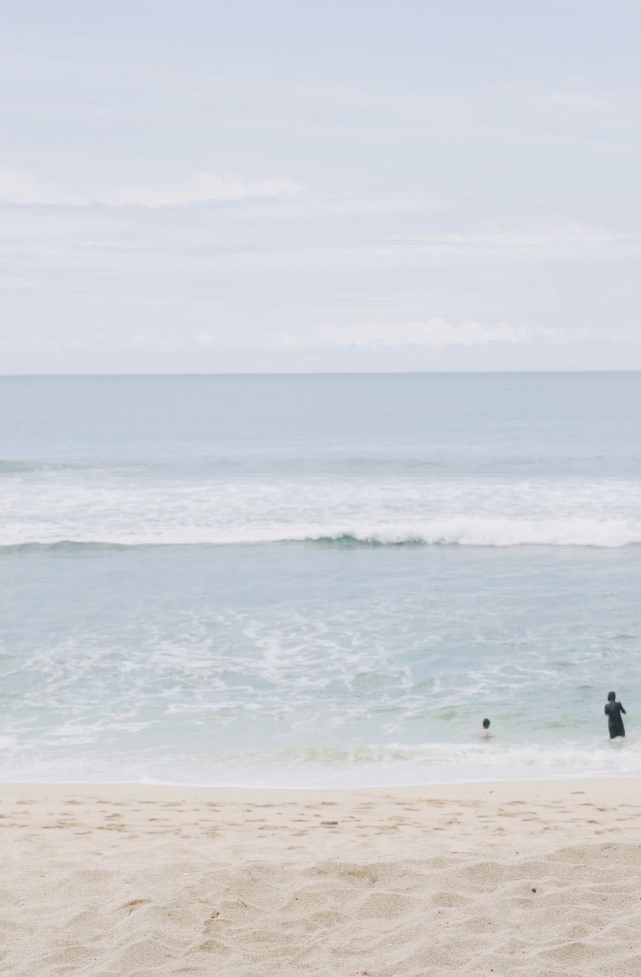 Load video: Woman standing in front of ocean wearing Surf_One_Piece_Lola_Black_Eco_Rib